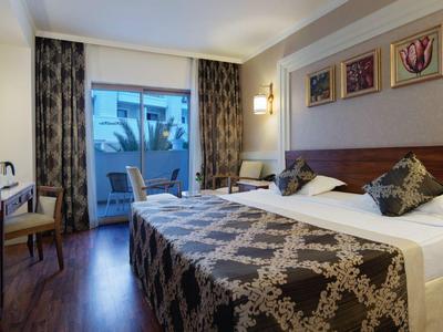 Příjemný hotelový pokoj s manželskou postelí, TV, balkonem a moderním vybavením.