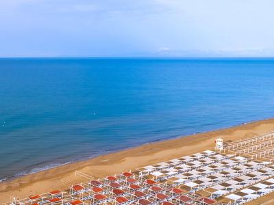 Leeg strand met rijen rode en witte parasols bij kalme zee