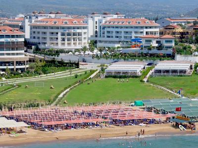 Grande hotel su una collina con vista sulla spiaggia e sul mare, con prati verdi nel mezzo.