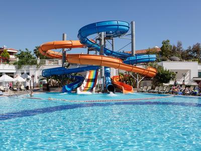 Grande piscina con scivoli d'acqua colorati e lettini nell'area dell'hotel.