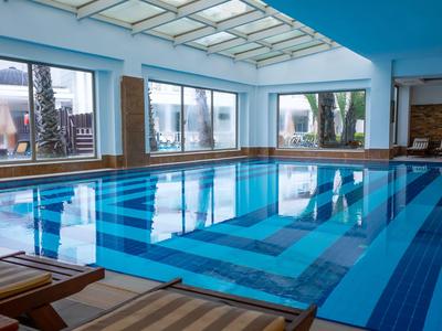 Piscina coperta con grandi finestre e lettini in un hotel.