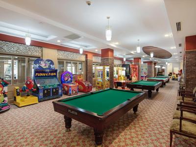 Een speelkamer met biljarttafels, arcadespellen en zitplaatsen, goed verlicht en ruim.