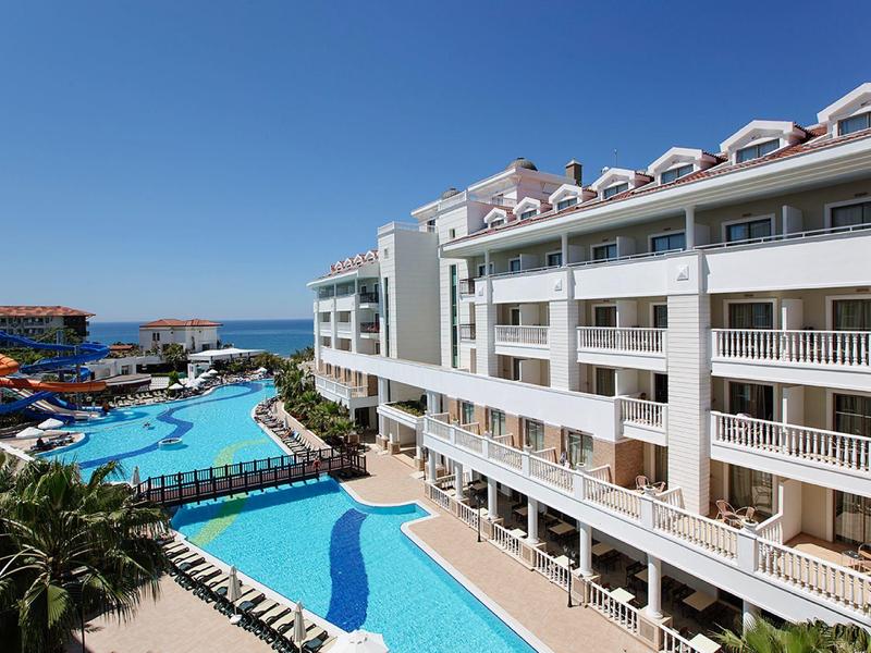 Velký hotel s několika bazény a výhledem na moře za jasné oblohy.
