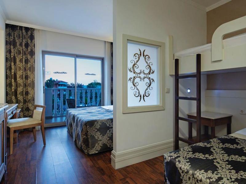 Moderně zařízený pokoj s manželskou postelí, palandou, dřevěným nábytkem a velkým oknem.