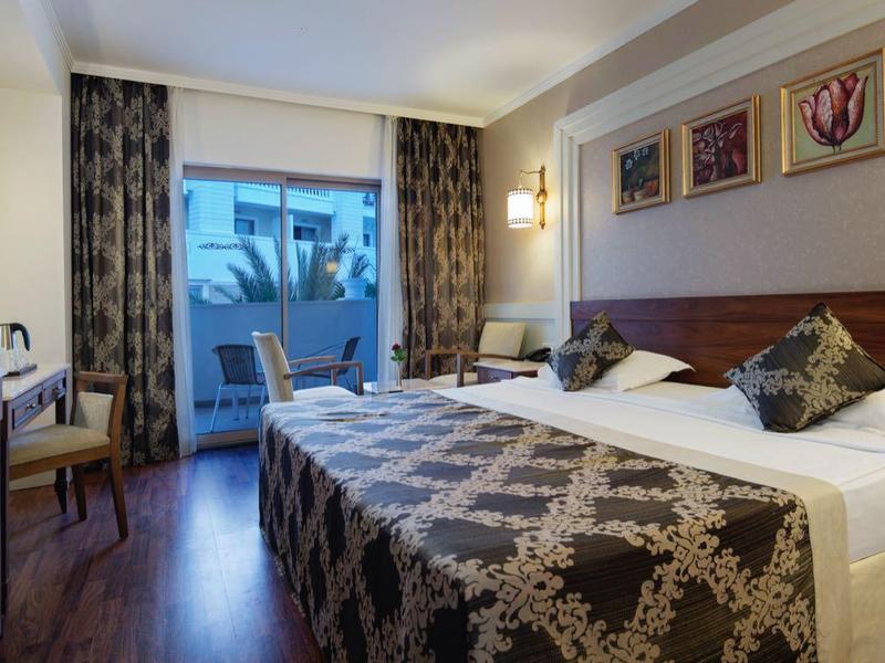 Příjemný hotelový pokoj s manželskou postelí, TV, balkonem a moderním vybavením.