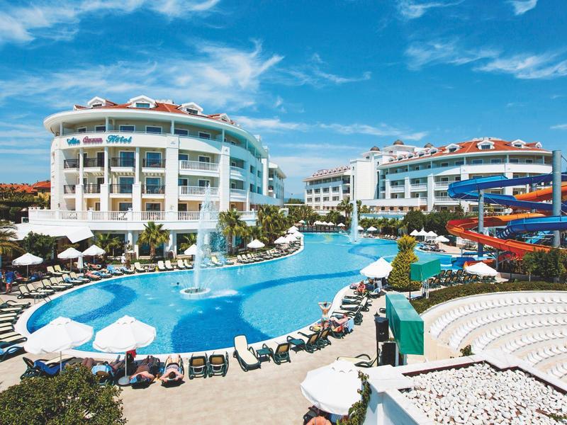 Moderní hotelový komplex s bazény, tobogány a lehátky pod modrou oblohou