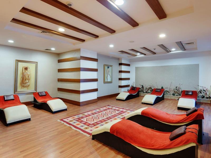 Moderní wellness místnost s pohodlnými lehátky, dřevěnou podlahou a uklidňujícím osvětlením.