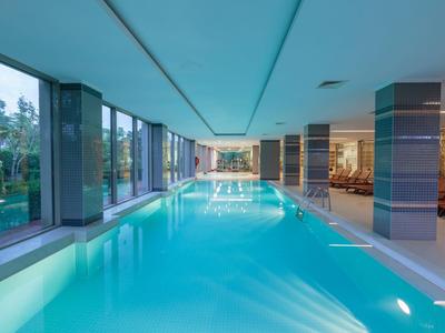 Heller Innenpool mit großen Fenstern und modernem Fitnessbereich nebenan.