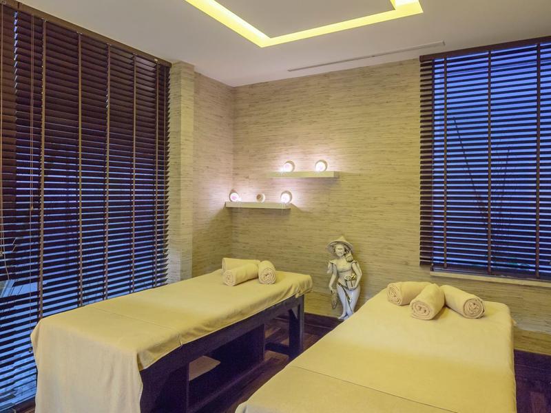 Ruhiger Wellnessraum mit zwei Massagetischen, sanfter Beleuchtung und Bambusjalousien.