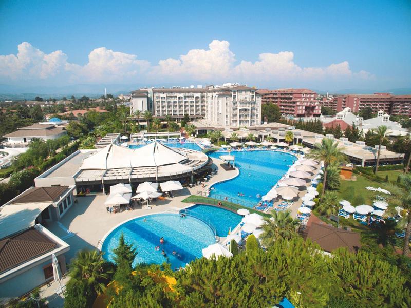Großes Hotelresort mit mehreren Pools, Sonnenschirmen und Liegestühlen unter klarem Himmel.