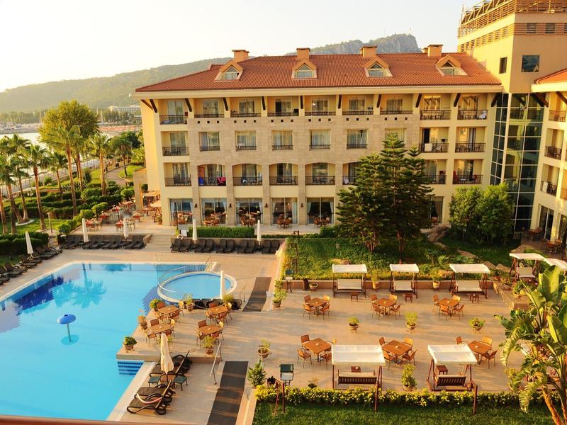 Hotel con grande piscina, terrazza solarium e vista sul mare al tramonto.