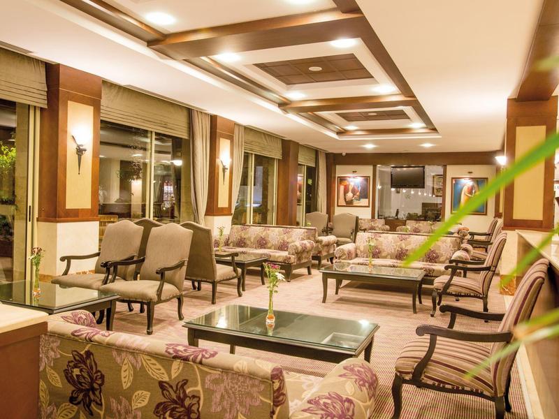 Area lounge dell'hotel accogliente con poltrone e divani imbottiti sotto luce calda.