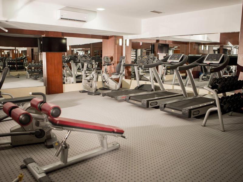 Palestra moderna con tapis roulant, panche per pesi e pareti a specchio in un hotel.