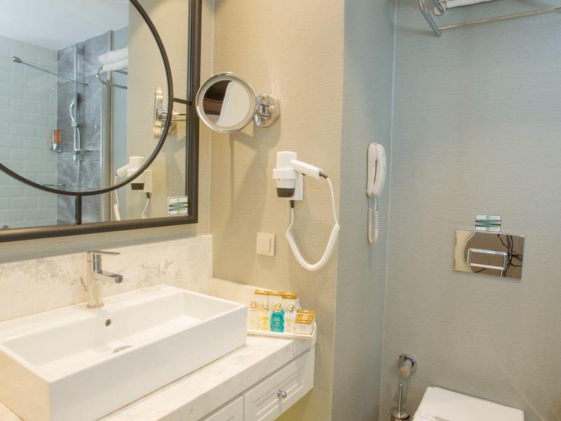 Bagno d'hotel moderno con lavabo, WC, asciugacapelli e porta asciugamani.