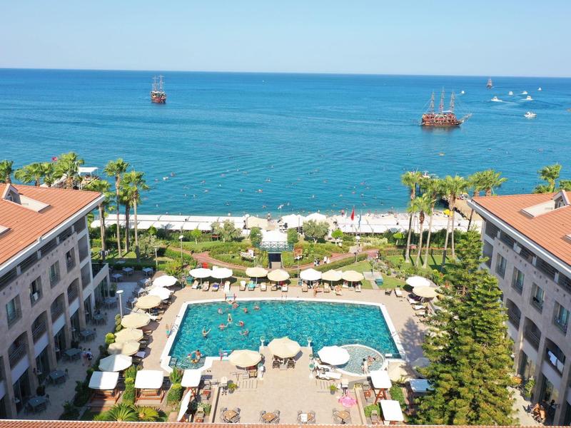 Vista di un'area piscina tra due hotel con vista mare e barche a vela.