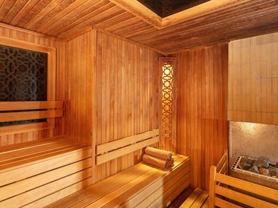 Dřevěná sauna s lavicemi a kameny pro relaxační chvíle odpočinku.