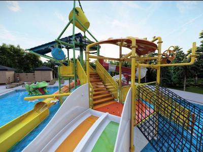 Barevné vodní skluzavky v otevřeném vodním parku s bazénem a jasnou oblohou.