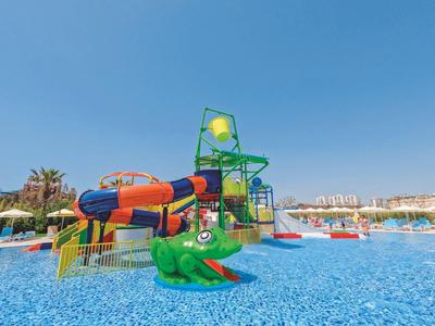 Vodní park s barevnými tobogány a brouzdalištěm, jasná modrá obloha.