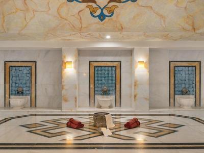 Prostorná hotelová hala s mramorovou podlahou a elegantními dveřmi na stěnách.