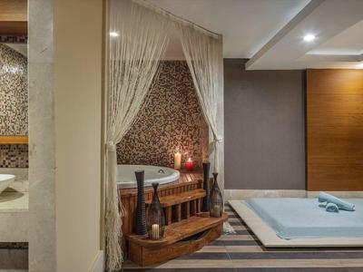 Hotelový apartmán s vířivou vanou, postelí king-size, teplým dřevěným zařízením a tlumeným osvětlením.