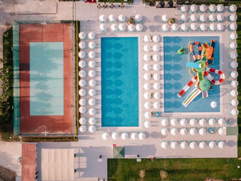 Letecký pohled na bazén, tenisový kurt a zónu se skluzavkou v hotelu.