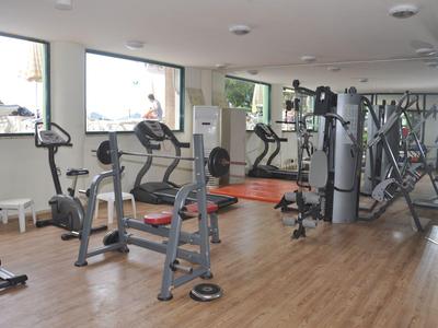 Palestra luminosa con varie attrezzature per allenamento e pavimento in legno.