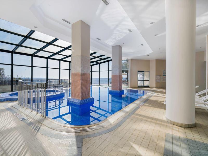 Área interior moderna con piscina, grandes ventanas y columnas en un hotel.