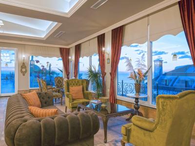 Espace lounge d'hôtel élégant avec grandes fenêtres et fauteuils confortables.