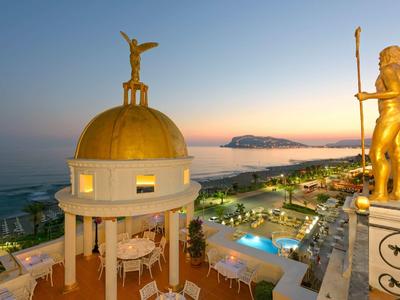 Hôtel de luxe avec statue dorée et dôme au coucher du soleil en bord de mer