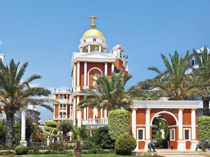 Bâtiment historique avec un dôme doré entouré de palmiers et jardins dans un lieu de voyage ensoleillé.