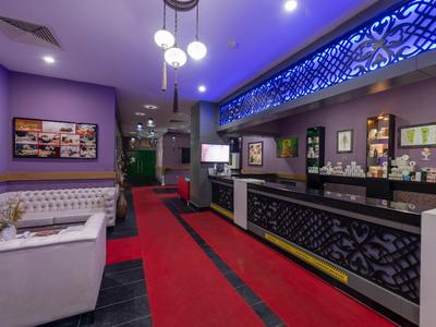 Hall d'hôtel élégant avec tapis rouge, murs violets et éclairage moderne.