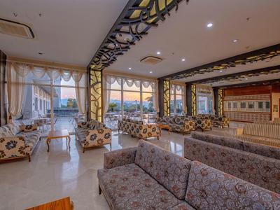 Espace lounge d'hôtel lumineux et spacieux avec divers canapés et grandes fenêtres.