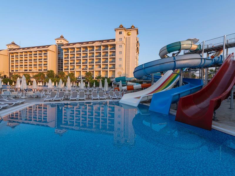 Hôtel avec grande piscine extérieure et toboggans colorés au coucher du soleil.