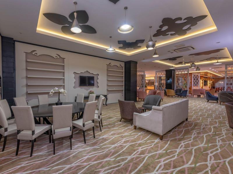 Espace moderne de hall d'hôtel avec fauteuils, canapés et table dressée.