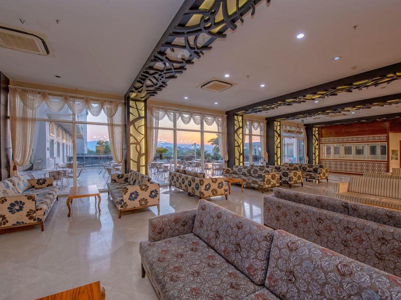 Espace lounge d'hôtel lumineux et spacieux avec divers canapés et grandes fenêtres.