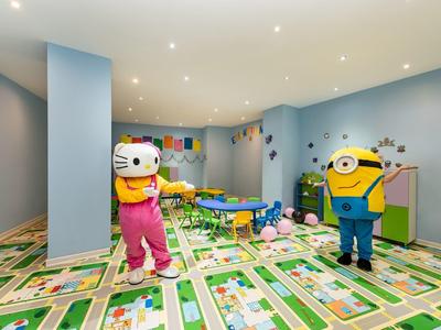 Barevná dětská herna s kreslenými postavičkami a výrazným kobercem v hotelu.