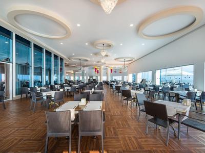 Prostorný, světlý hotelový jídelní prostor s moderním nábytkem a velkými okny.