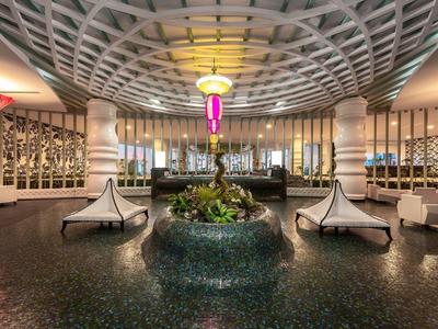 Prostorná moderní hotelová lobby s dekorativním vzorem stropu a stylovým posezením.