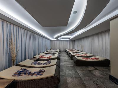 Elegante area benessere con più lettini, illuminazione d'atmosfera e tende alle pareti.