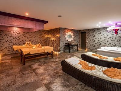 Accogliente sala benessere con due lettini da massaggio e illuminazione rilassante.