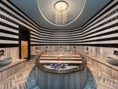 Luxusní hammam s mramorovými stěnami, centrálním umyvadlem a starožitným osvětlením.