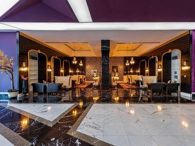 Elegantní hotelová lobby s moderními posezeními, teplým osvětlením a mramorovou podlahou.