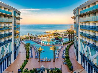 Vista di una piscina dell'hotel tra due edifici con vista sul mare al tramonto.