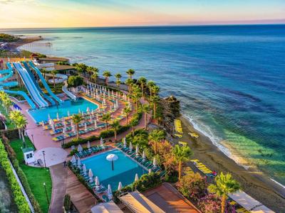 Vista di un resort con piscine e scivoli d'acqua lungo la costa al tramonto.