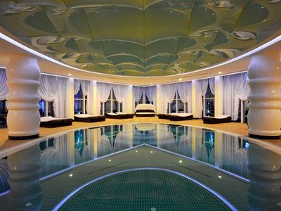 Elegantní krytý bazén se sloupy, zakulaceným stropem a pohodlnými lehátky v noci.
