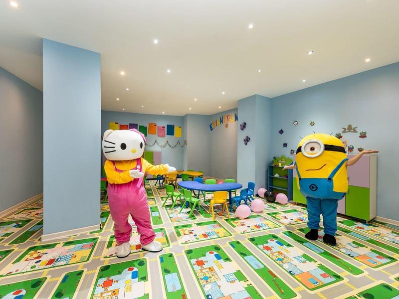 Barevná dětská herna s kreslenými postavičkami a výrazným kobercem v hotelu.