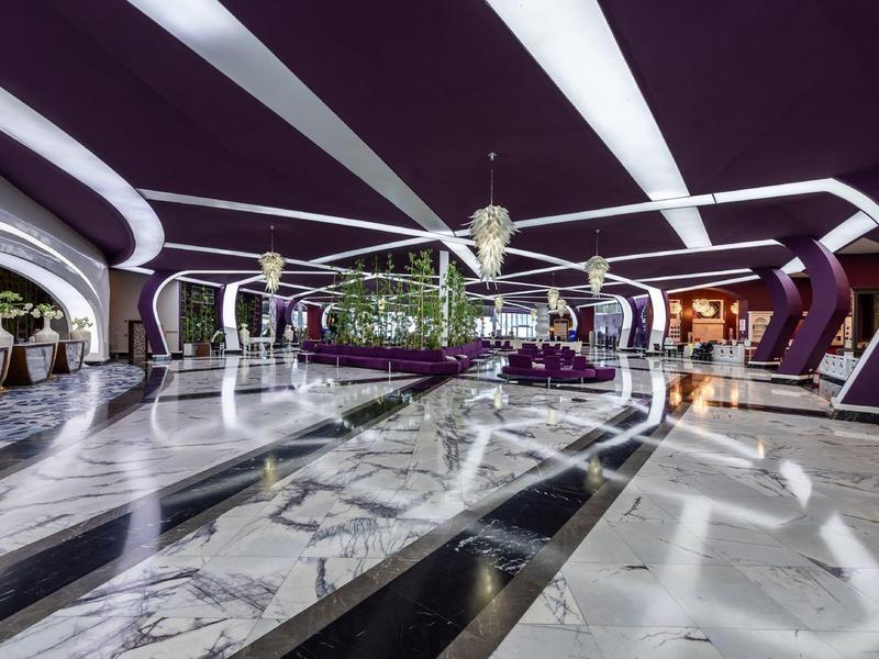 Moderní hotelová lobby s uměleckým designem a lesklou mramorovou podlahou.