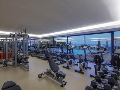 Palestra moderna con attrezzature e grandi finestre con vista notturna sulla città.