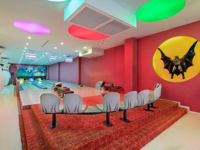 Pista da bowling colorata con birilli e decorazione di pipistrello sulla parete in uno spazio interno moderno.