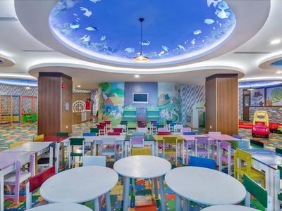 Světla herna pro děti s kulatými stoly a barevnými hrami, moderní zařízení.